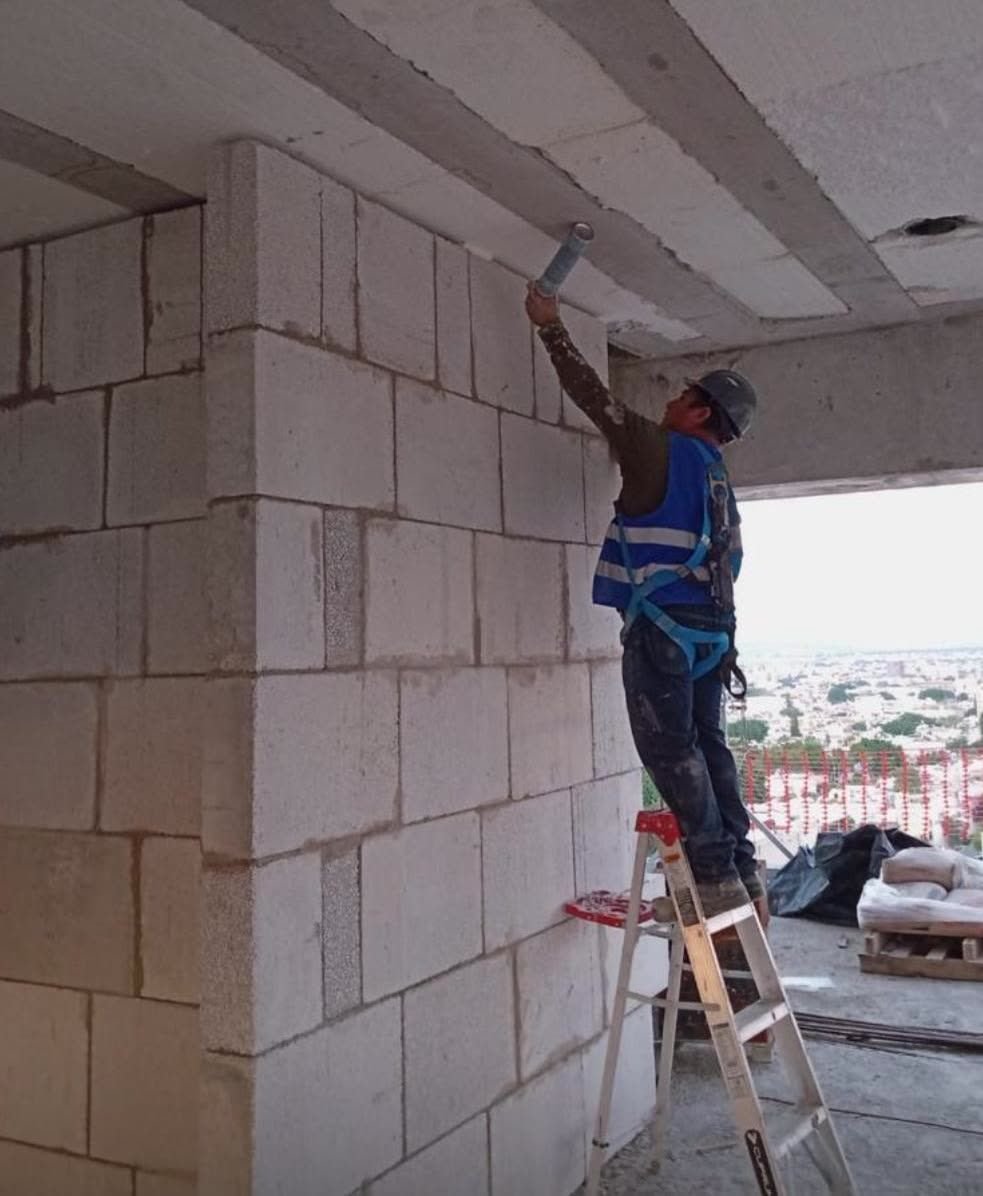 Muro divisorio de bloques de concreto celular levantado hasta la losa en un edificio en obra.