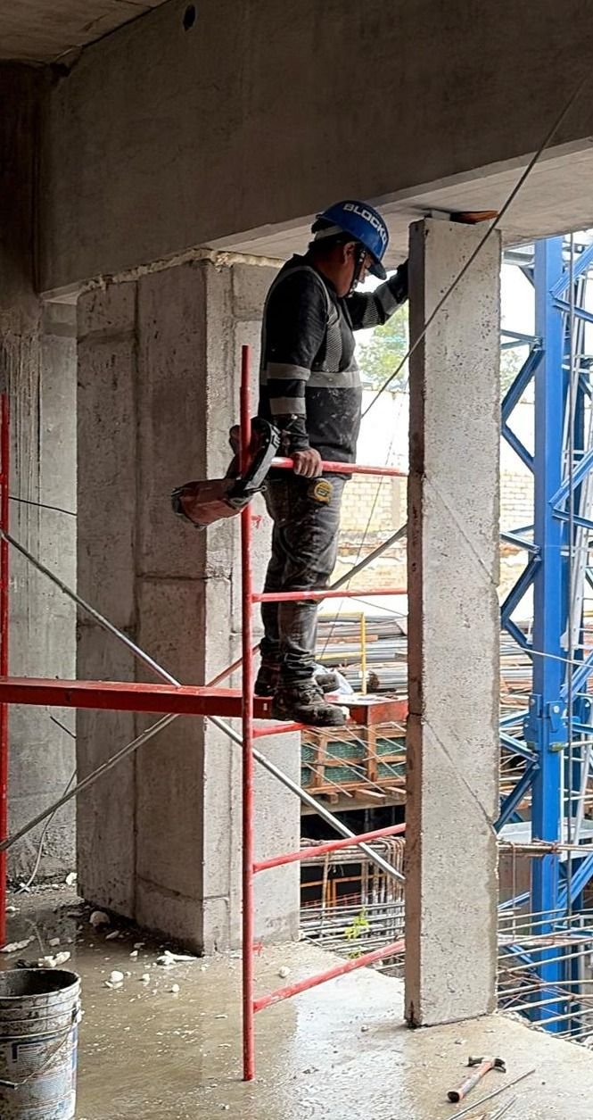 Instalador sobre andamio colocando un panel de concreto aligerado en un muro de obra.