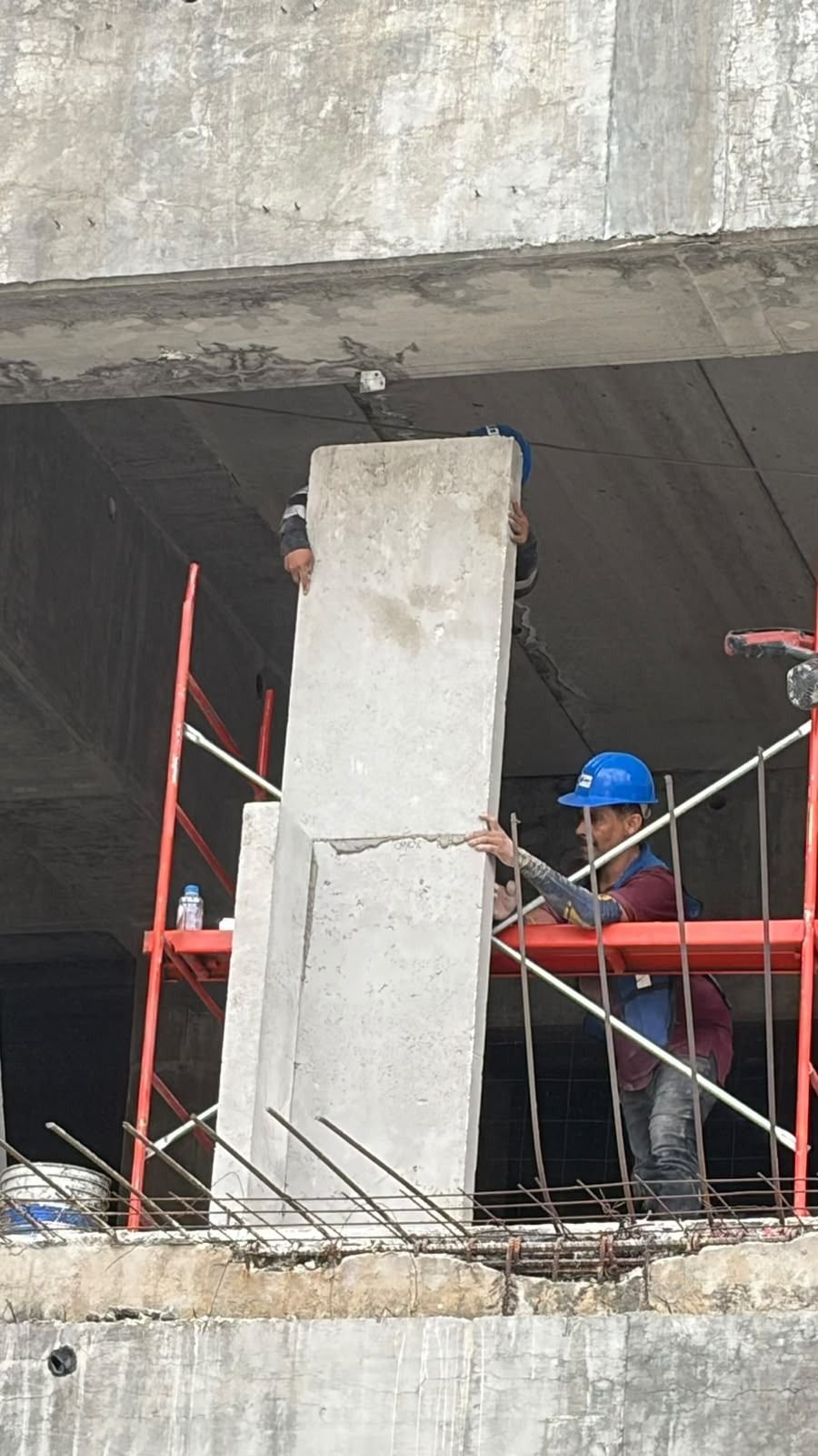 Dos trabajadores izan un panel BLOCKO a su lugar dentro de un marco de concreto.