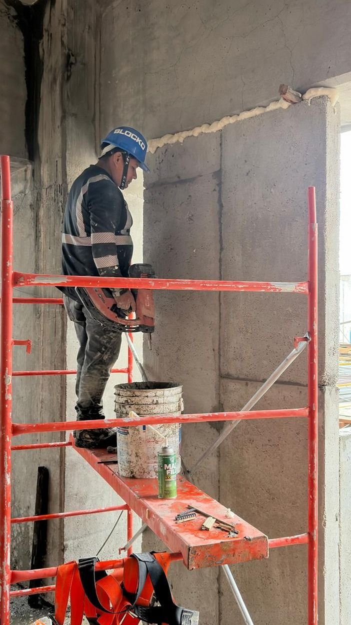 Instalador con casco sobre andamio ajustando paneles BLOCKO.