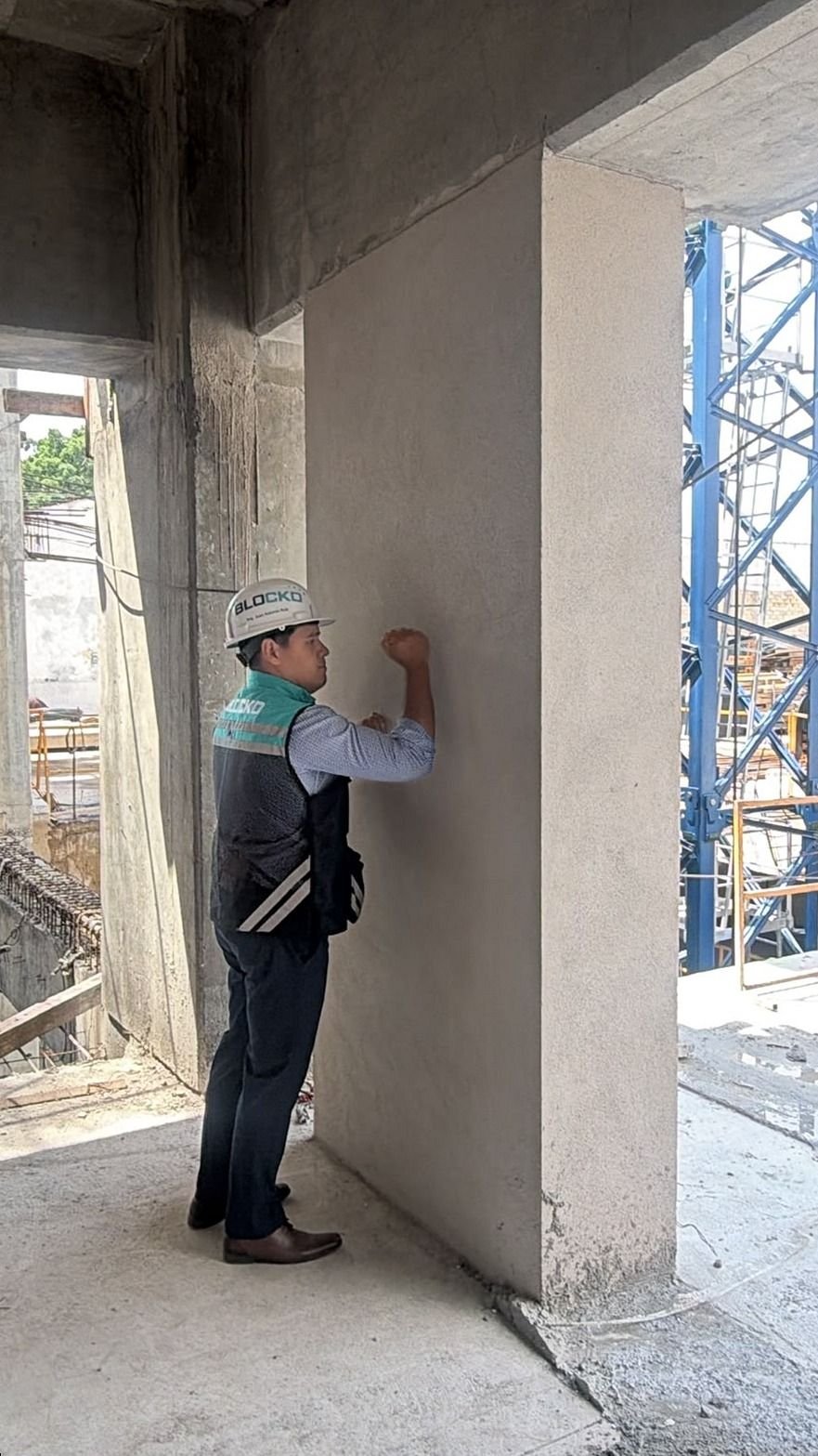 Ingeniero revisando un muro divisorio de paneles de concreto aligerado ya colocado en un edificio en obra.